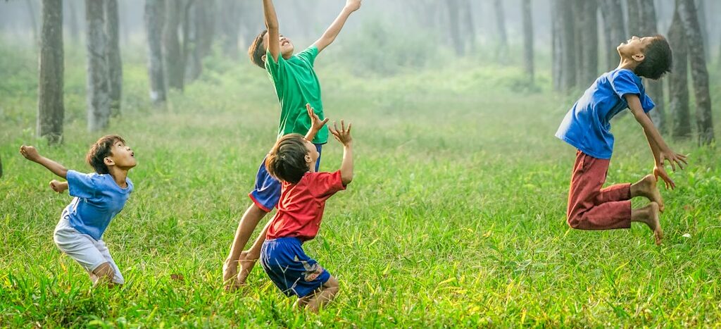 four boy playing ball on green grass